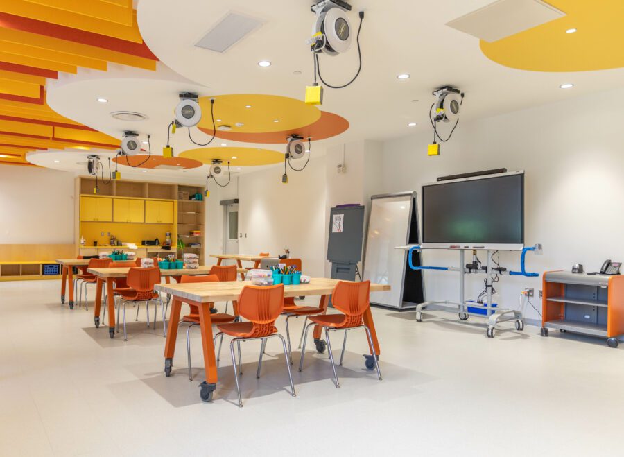 Modern classroom with collaborative workstations and colorful ceiling design.