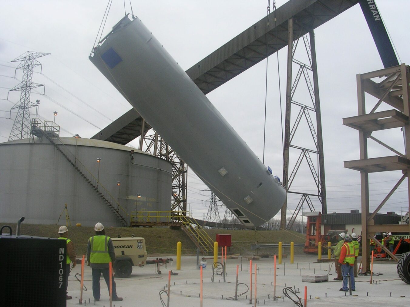 Construction workers surveying a silo being set by crane