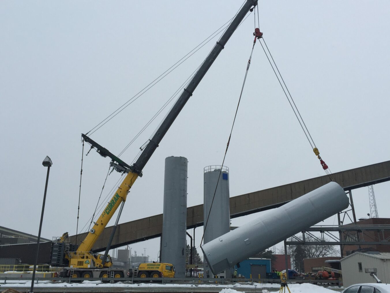 Large crane with pulley setting a silo in place