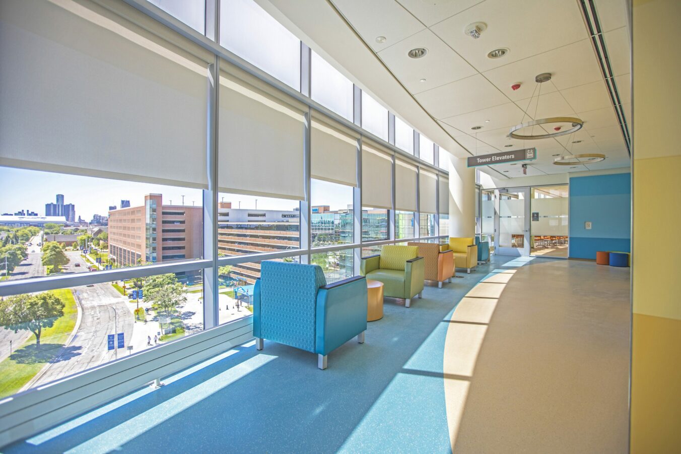 Elevator Bank Area of Children's Hospital. Along sun-filled windows are colorful lounge waiting chairs.