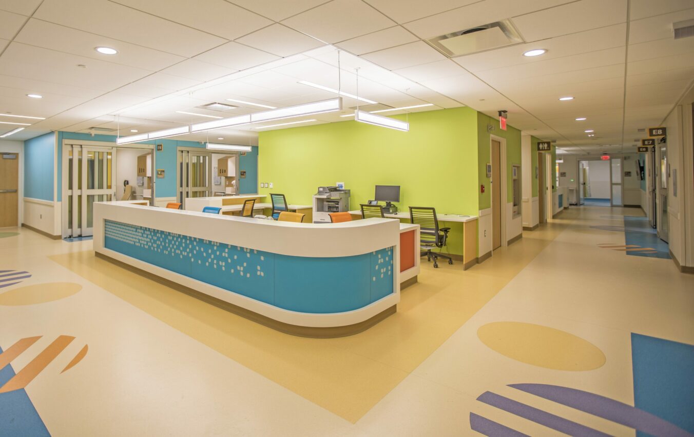 Brightly-lit reception desk of Chidlren's Hospital surrounded by colorful walls and abstract graphics on the floors.