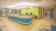 Brightly-lit reception desk of Chidlren's Hospital surrounded by colorful walls and abstract graphics on the floors.