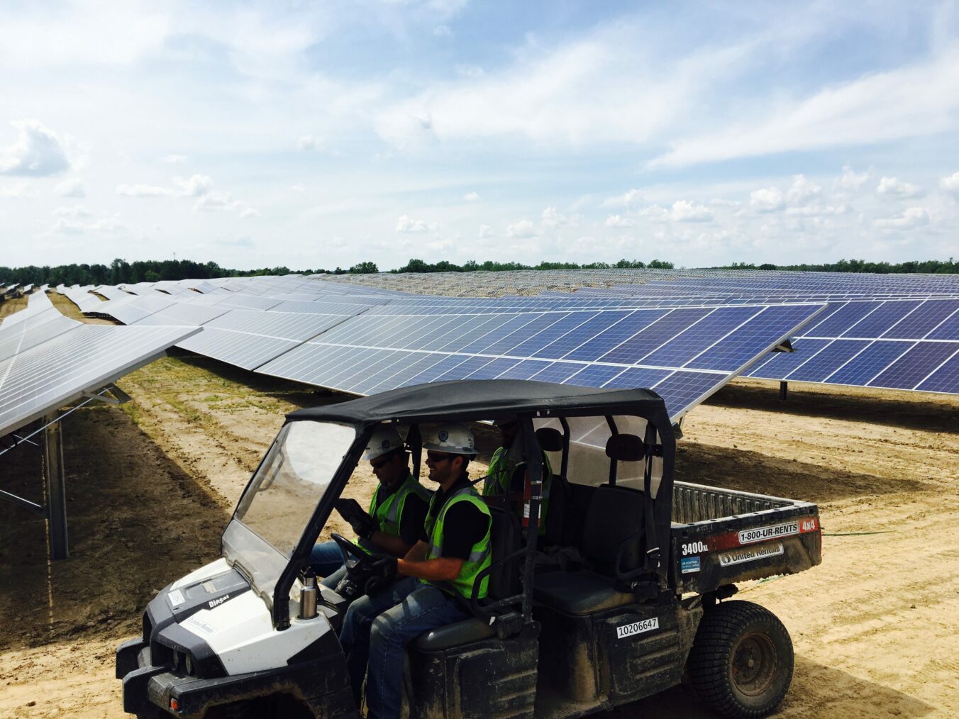 Construction workers driving ATV through solar farm