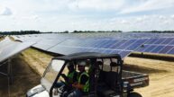 Construction workers driving ATV through solar farm