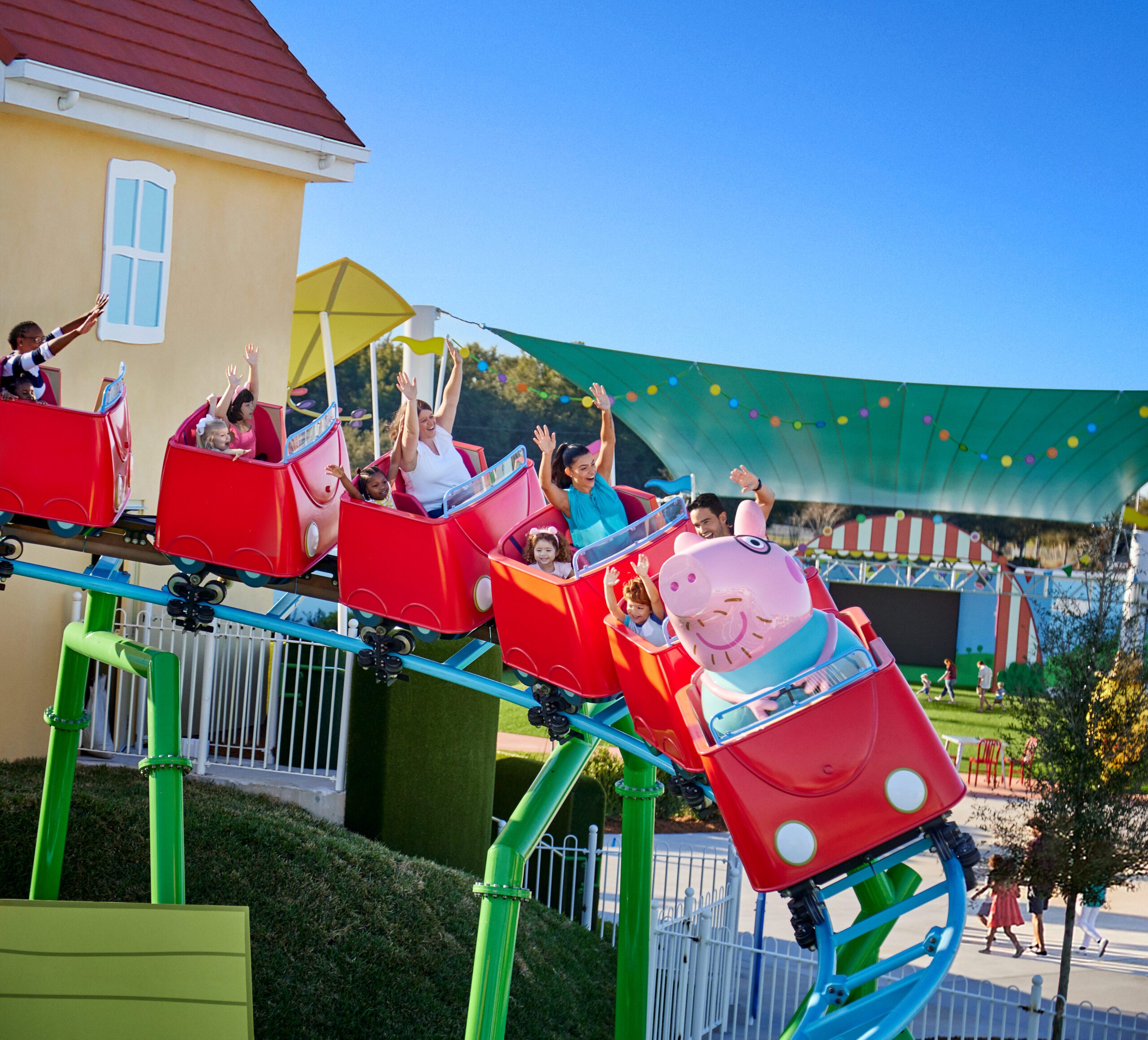 Kids and parents ride the red rollercoaster with their hands high