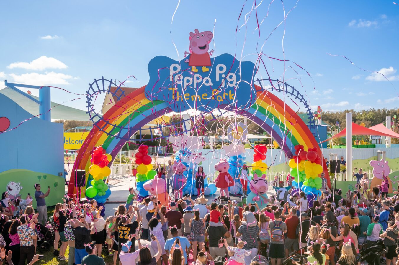 Guests celebrate the grand opening of Peppa Pig Theme Park infront of its colorful entrance